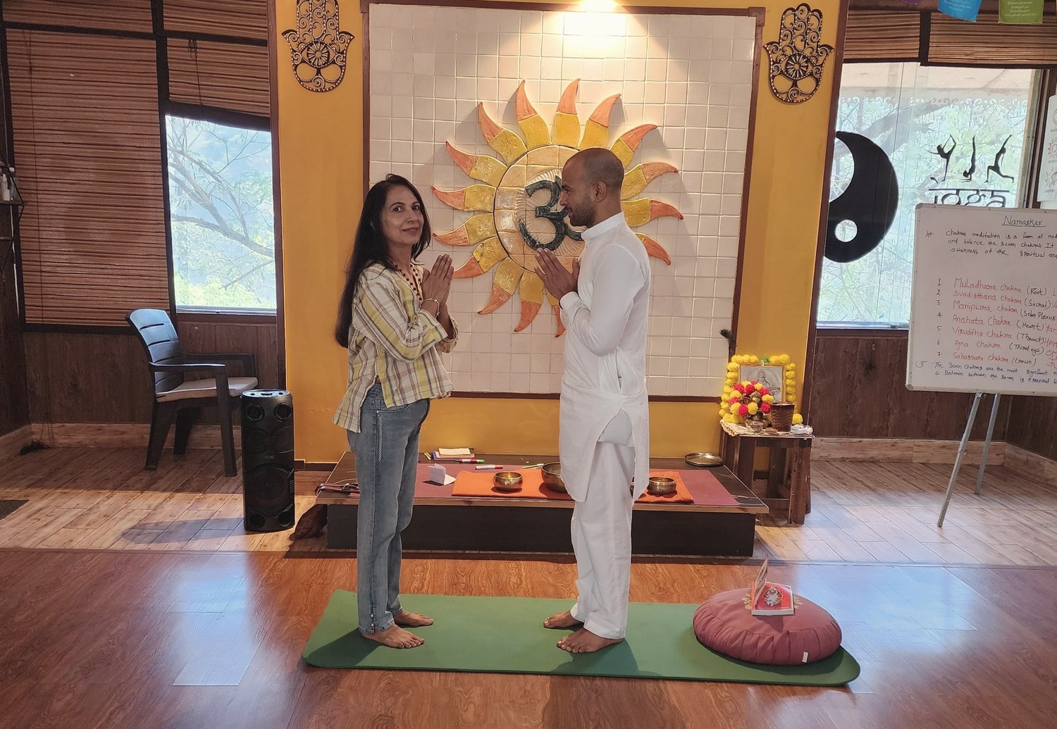 Neetu in namaste with a client inside a warm, calming meditation studio