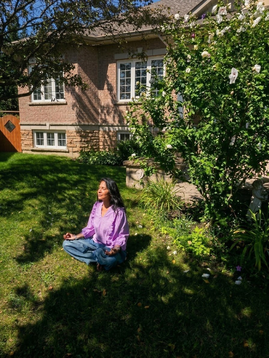 Neetu sitting cross-legged in a meditative pose in a sunlit backyard garden
